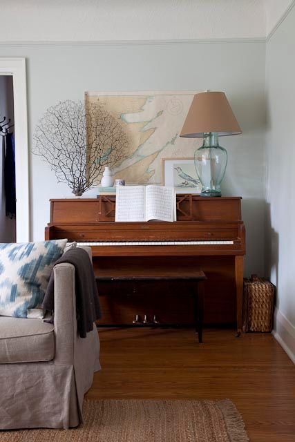 a living room filled with furniture and a piano in front of a painting on the wall