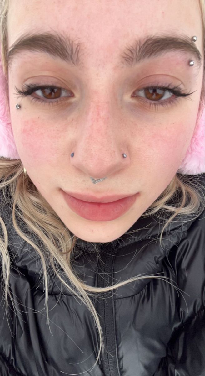 a woman with freckles and piercings on her nose