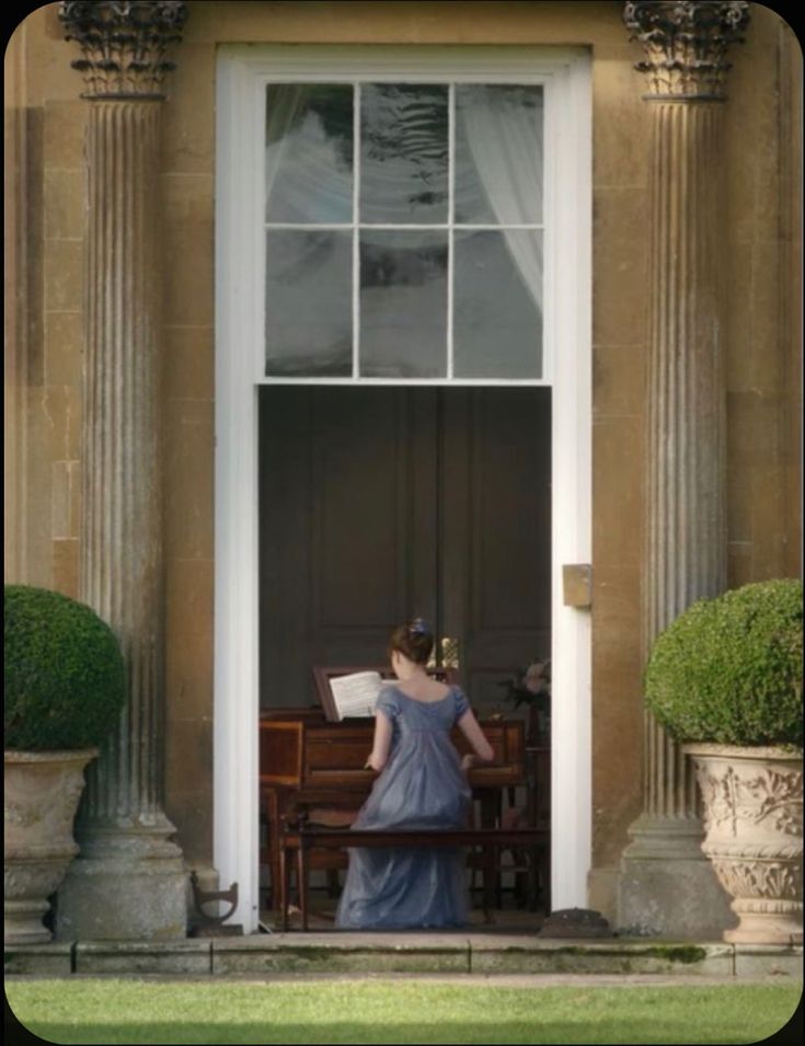 a woman in a blue dress is standing at the entrance to a building with columns