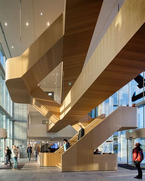 people are walking up and down the stairs in an office building with large windows on both sides