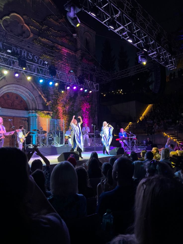 a group of people standing on top of a stage in front of a large crowd