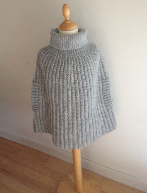 a mannequin is wearing a gray sweater on a wooden stand in front of a white wall