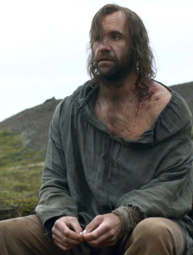 a man with long hair sitting on the ground