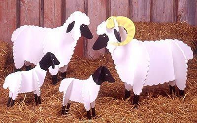 three sheep are standing in the hay with a yellow hat on their head and one is black and white