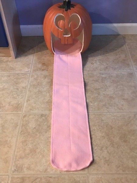 an orange pumpkin sitting on top of a pink table cloth next to a blue wall