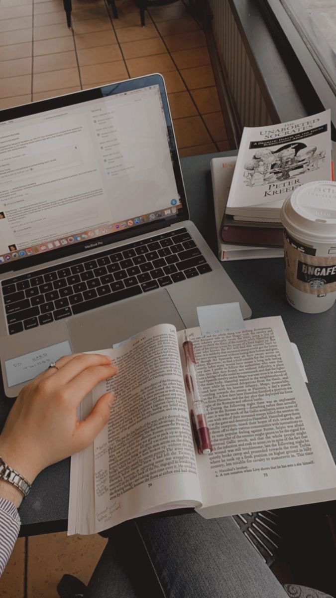 a person sitting at a table with an open book and laptop