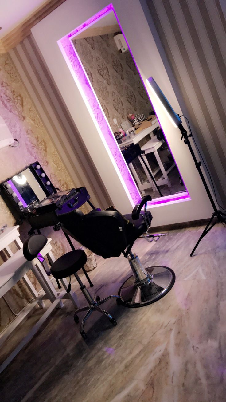 a salon chair sitting in front of a mirror with purple lights on the wall behind it