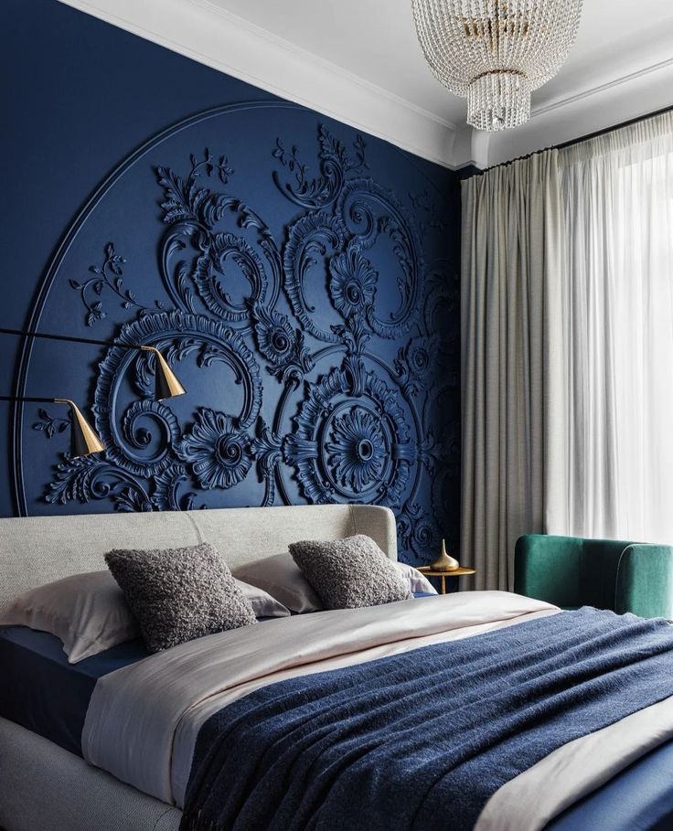 a large bed sitting under a blue wall next to a chandelier and window