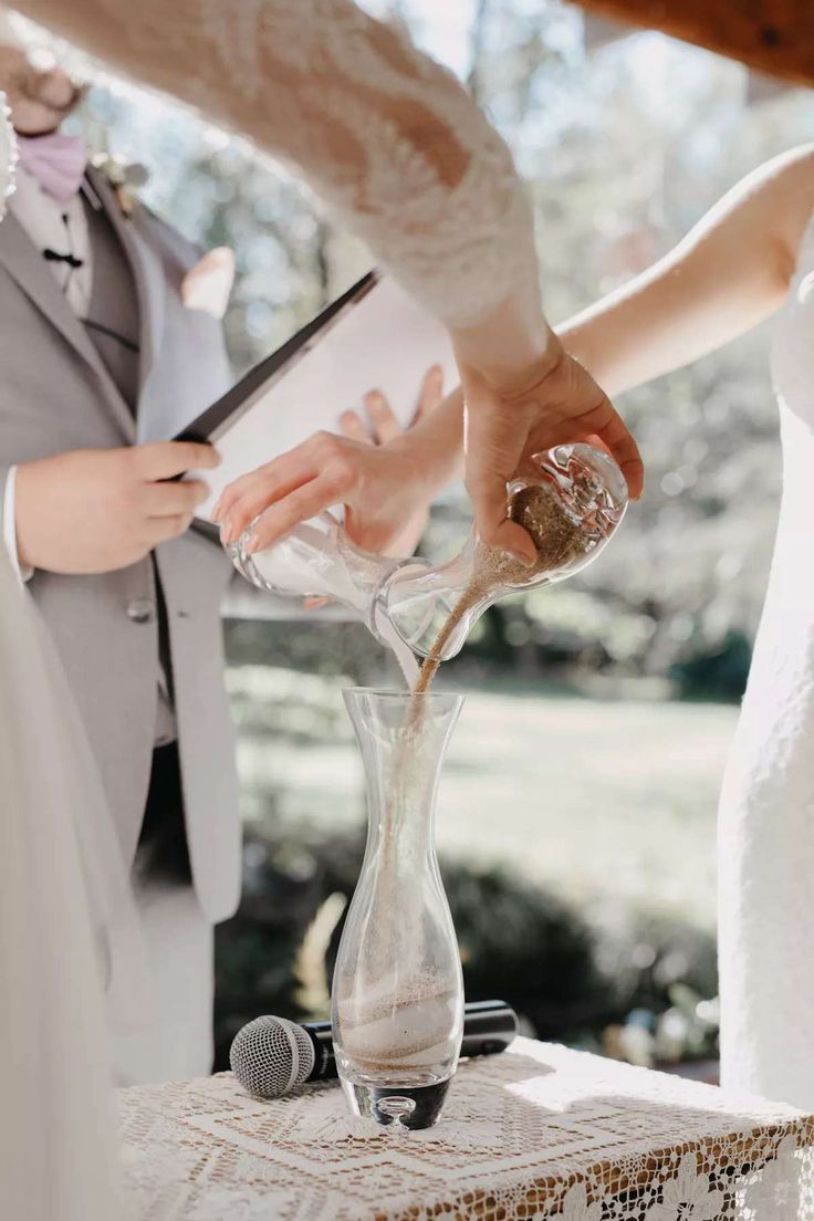 the bride and groom are pouring sand into a vase