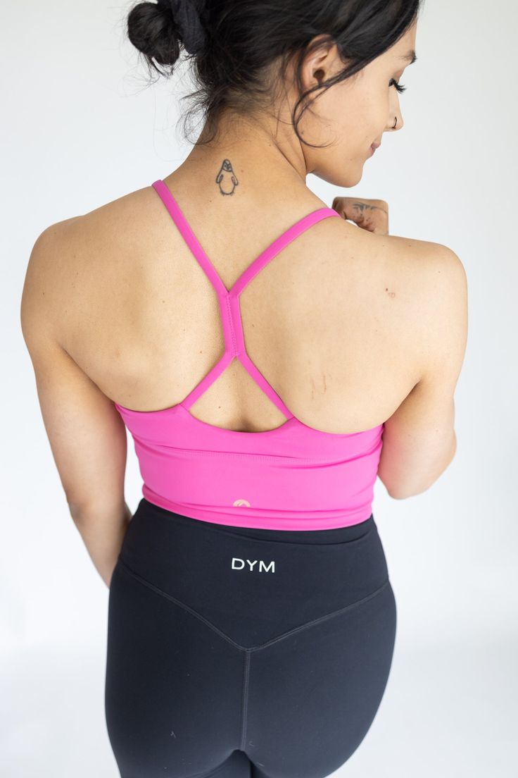 a woman in black and pink sports bra top with her back turned to the camera