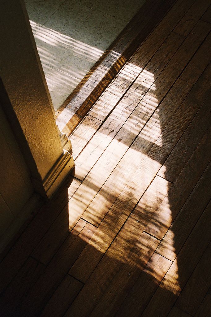 an open door with the light coming through it and shadows on the floor behind it