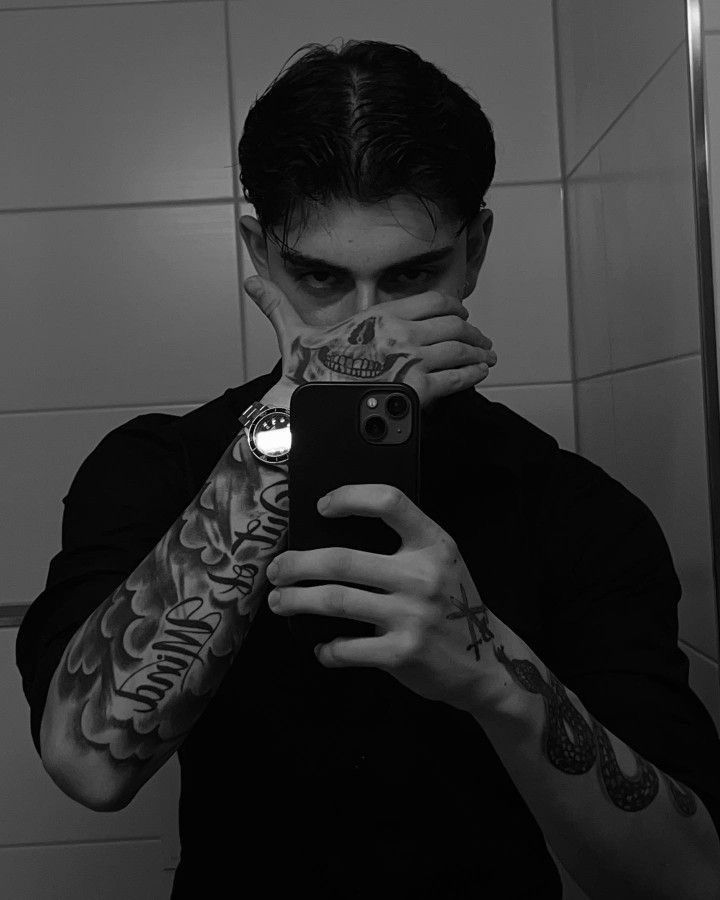 a man taking a selfie in the mirror with tattoos on his arms and shoulder