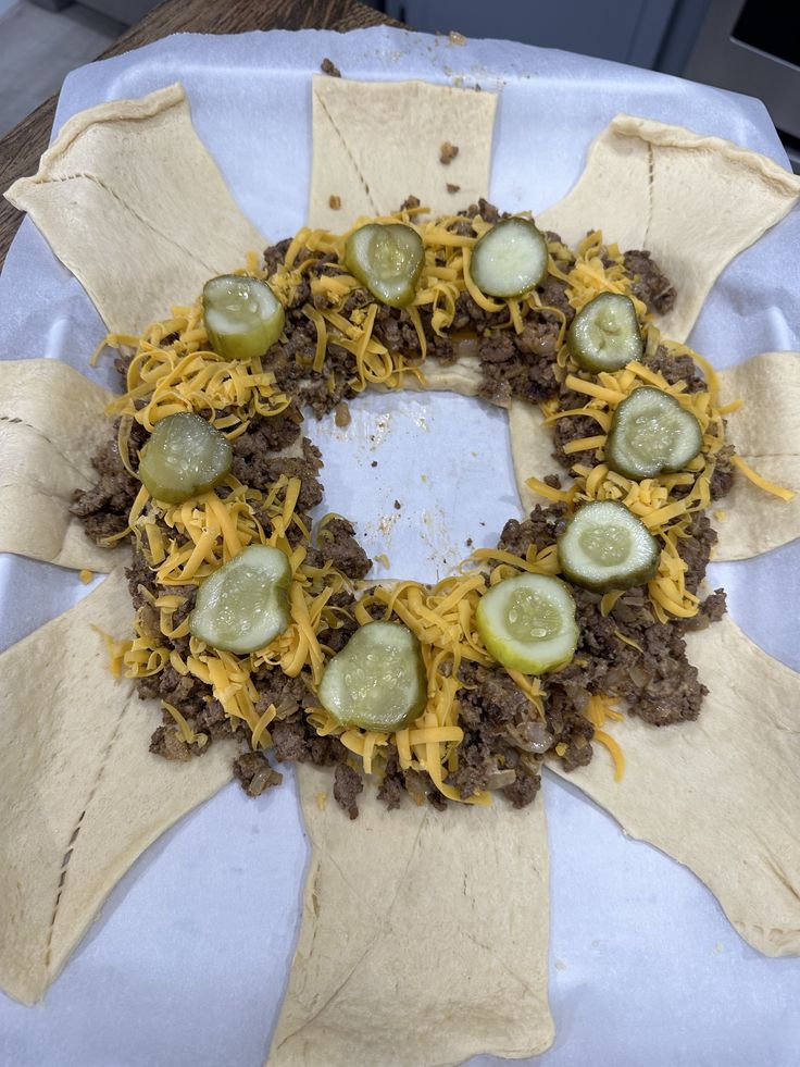 a wreath made out of tortilla shells with cheese and pickles on top