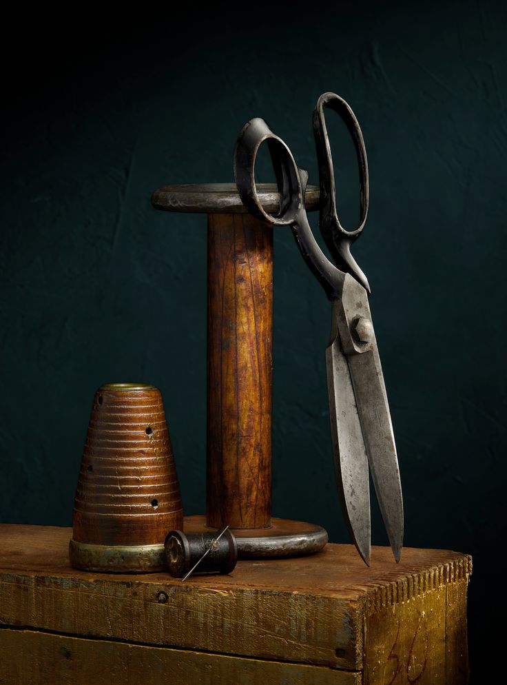 a pair of scissors sitting on top of a wooden box next to a thimble