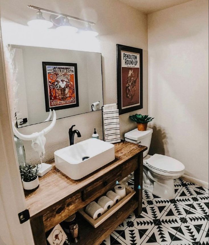 a bathroom with black and white flooring and artwork on the wall above the sink