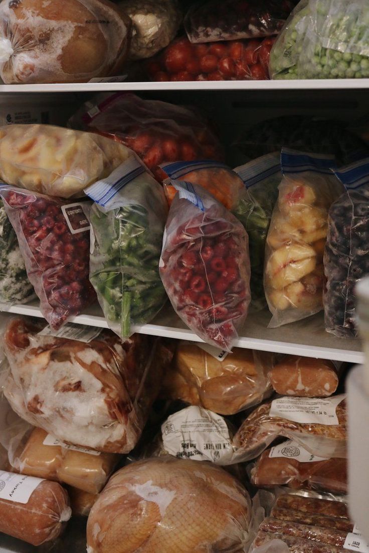 an assortment of fruits and vegetables on shelves in a grocery store with plastic bags over them