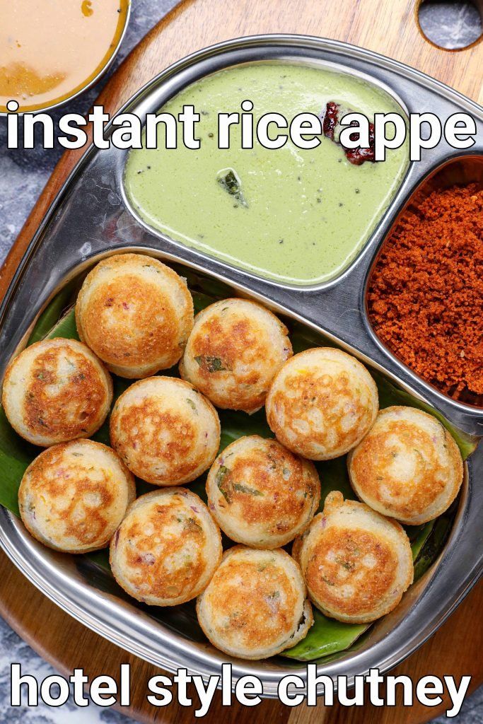 a metal tray filled with food next to a bowl of green sauce and spoons