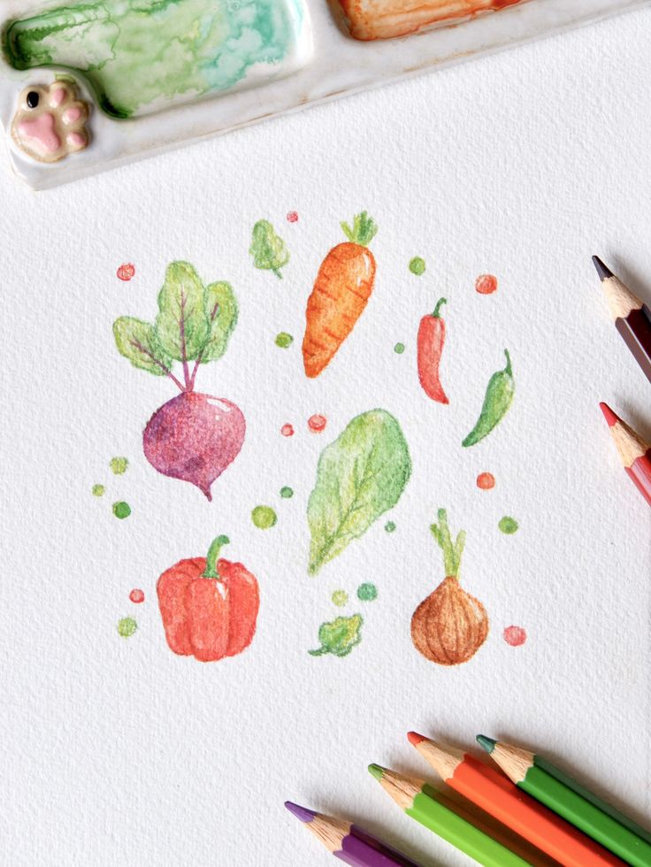 some colored pencils are laying on top of a paper with vegetables painted on it