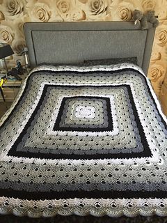 a crocheted bedspread on a bed in a room with roses behind it