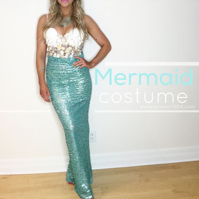 a woman standing in front of a white wall wearing a green sequin mermaid costume