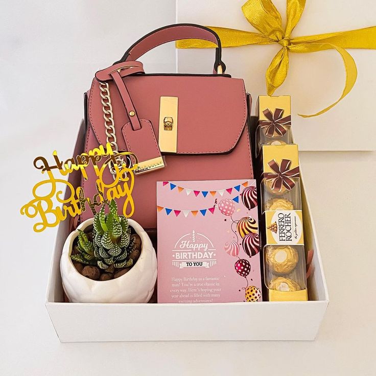 a pink purse and some chocolates in a white box with a yellow ribbon around it