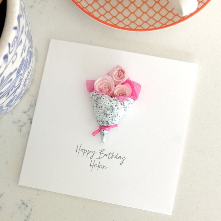 a happy birthday card with pink roses on it next to a cup and saucer