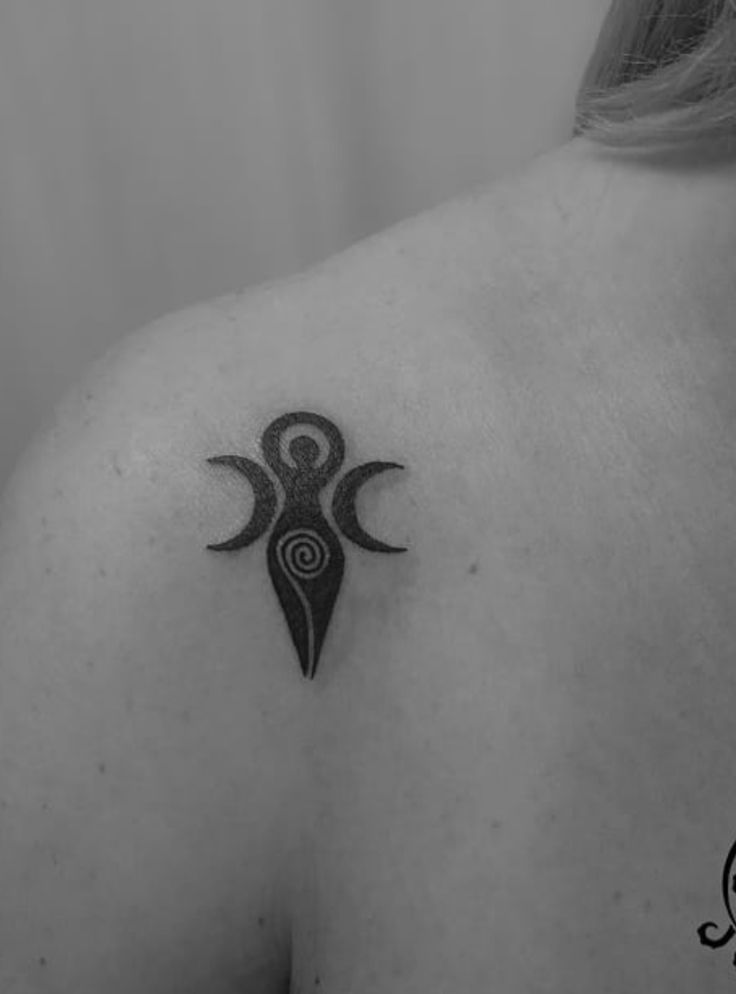 a woman's back with a tattoo design on her left shoulder and an arrow in the middle