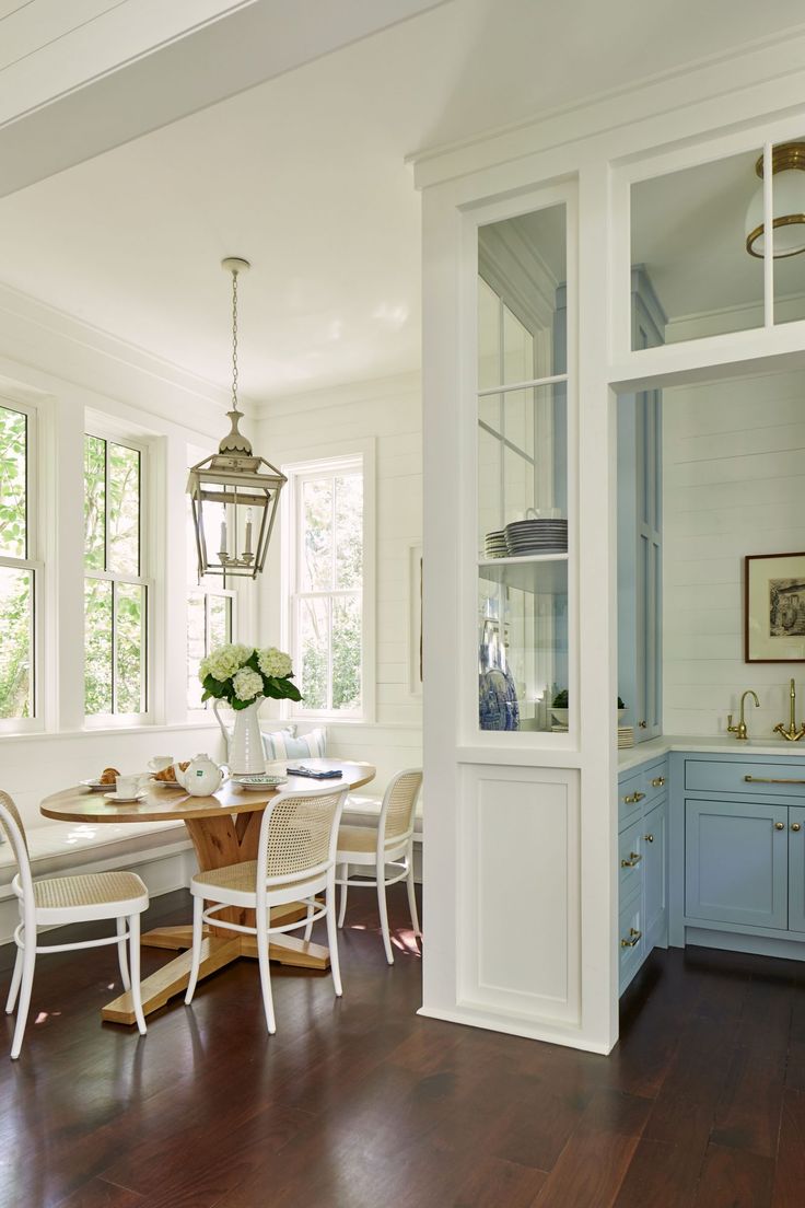 the dining room table is surrounded by white chairs and blue cabinets with glass doors that lead to an outdoor patio