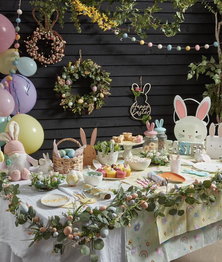 a table topped with lots of food and bunnies next to some balloons in the background