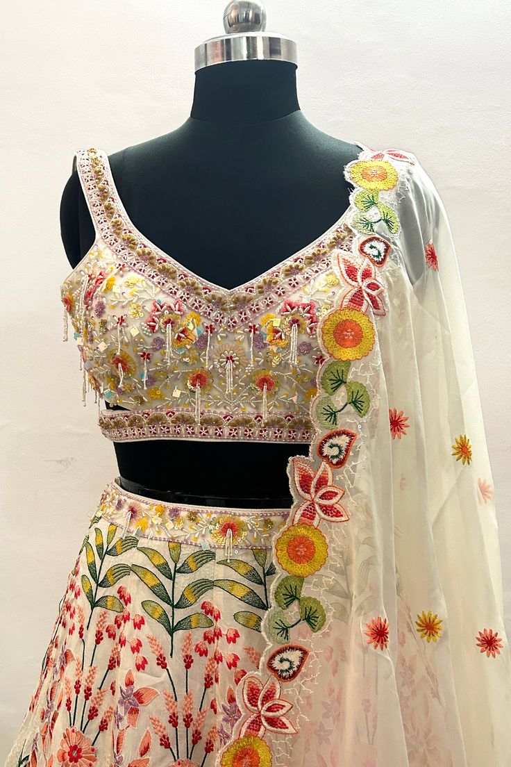 This Lehenga Choli is Ready to Wear Featuring an ivory lehenga in Chinon Silk base with rainbow Color hand embroidery. It is paired with a matching blouse. Style it with statement jewellery and heels for a wedding or an engagement ceremony, showcasing style and sophistication. Lehenga Fabric - Chinon Silk Blouse Fabric: Net Inner Fabric - Silk Dupatta Fabric - Georgette Color _ Ioory & Multi Color Style - Engagement ceremony Lehenga Embroidery -stones, Thread & Sequence Work NOTE : Originally st Off White Sharara With Floral Embroidery For Festive Occasions, Festive Off White Sharara With Floral Embroidery, Off White Floral Embroidered Sharara For Festive Occasions, Designer White Sharara With Floral Embroidery, Floral Embroidered Party Wear Lehenga With Traditional Drape, Party Wear Lehenga With Floral Embroidery, Unstitched Cream Lehenga, Embellished Multicolor Anarkali Set With Traditional Drape, Multicolor Embellished Anarkali Set With Traditional Drape