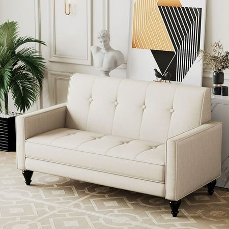 a living room with a white couch and art on the wall next to a potted plant