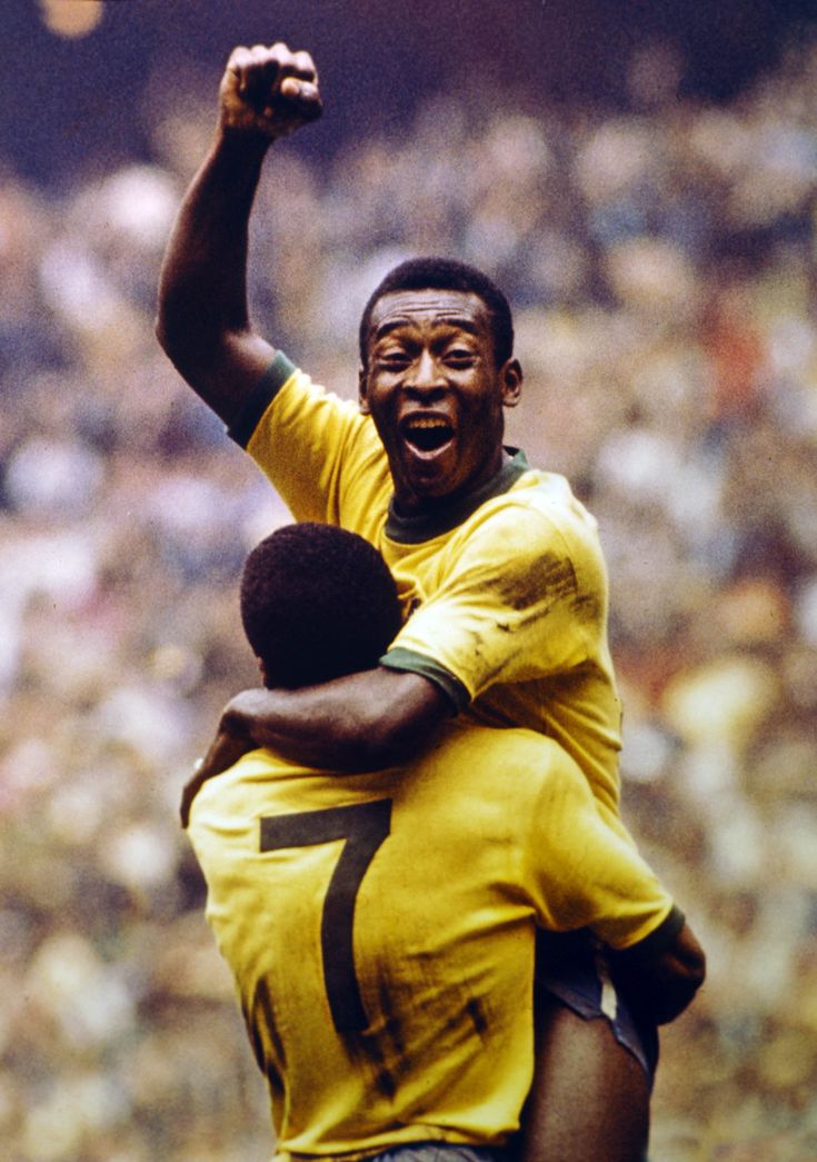 two soccer players hugging each other in front of an audience at a sporting event, with one holding the other's arm up