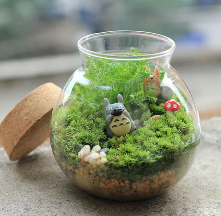 a glass jar filled with plants and small figurines