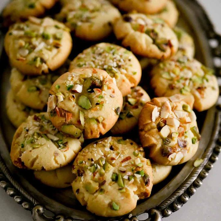 a plate full of cookies with nuts and pistachios on top, ready to be eaten