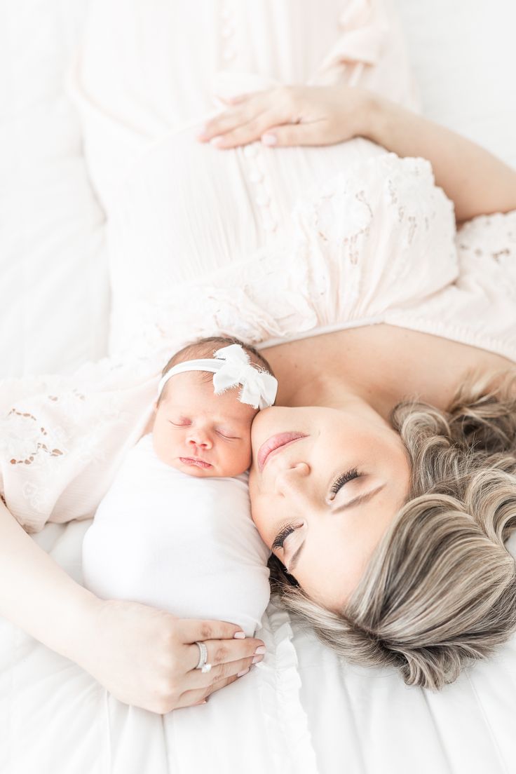 a woman laying on top of a bed holding a baby