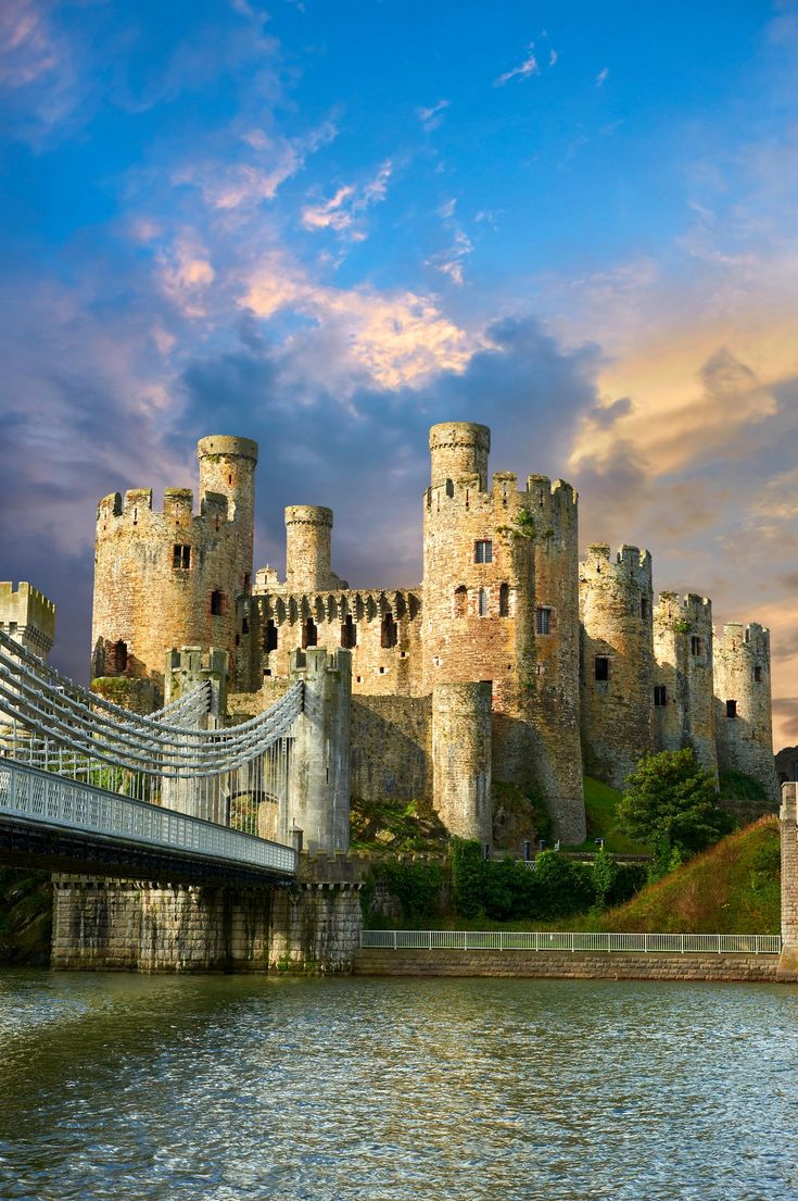 an old castle with a bridge going across it and the sky in the back ground