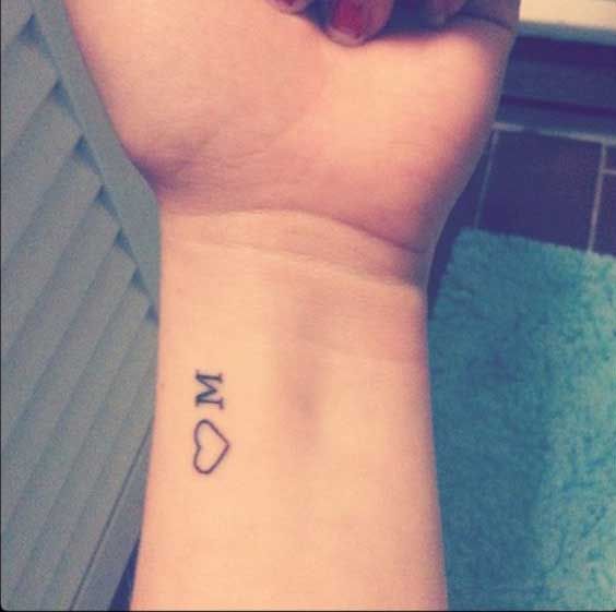 a woman's wrist tattoo with the word love written on it