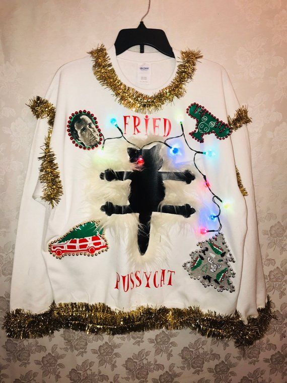 a white sweater with christmas lights on it and a black cat hanging from the front