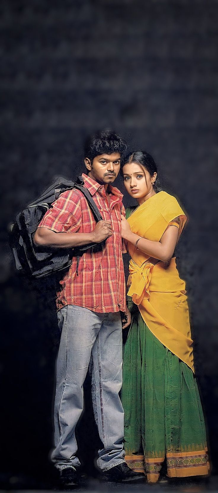 two people standing next to each other in front of a dark background with one person wearing a yellow and green sari