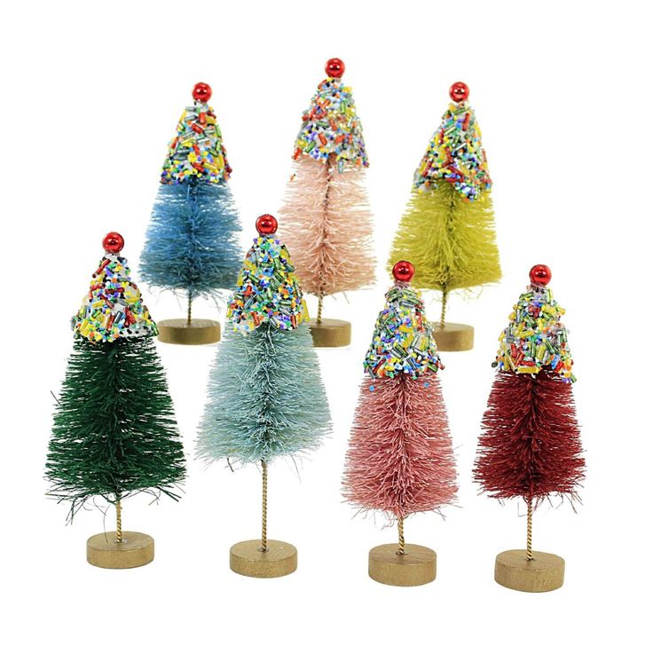 small christmas trees in different colors and sizes on wooden bases, each decorated with candy