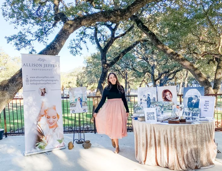 a woman standing in front of a table with pictures on it and an information board