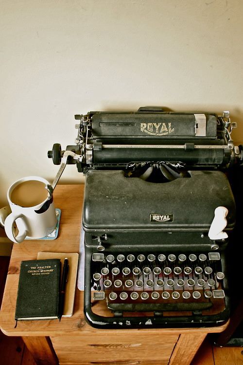 an old - fashioned royal typewriter sits on a desk next to a cup of coffee