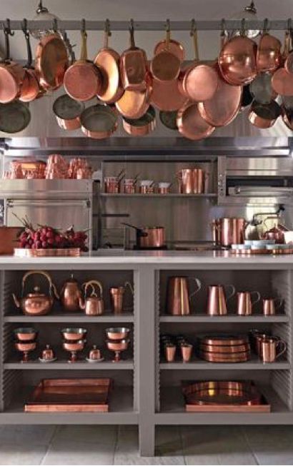 pots and pans are hanging from the ceiling in a large kitchen with stainless steel cabinets