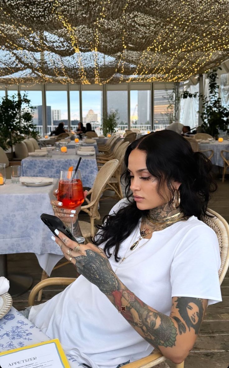 a woman sitting in a chair holding a smart phone and looking at her cellphone