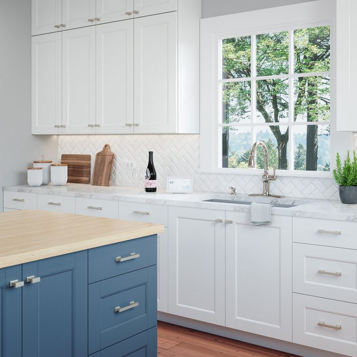 a kitchen with white cabinets and marble counter tops, gold pulls on the handles in front of an open window