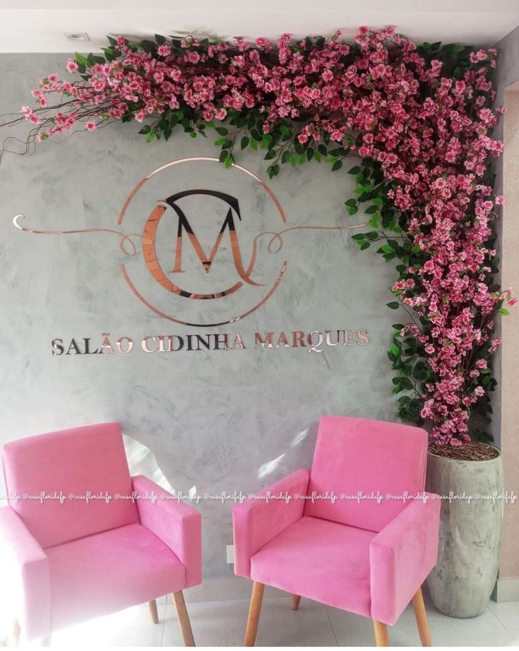 two pink chairs sitting next to each other in front of a wall covered with flowers