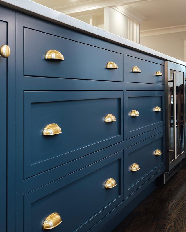 a kitchen with blue cabinets and brass pulls