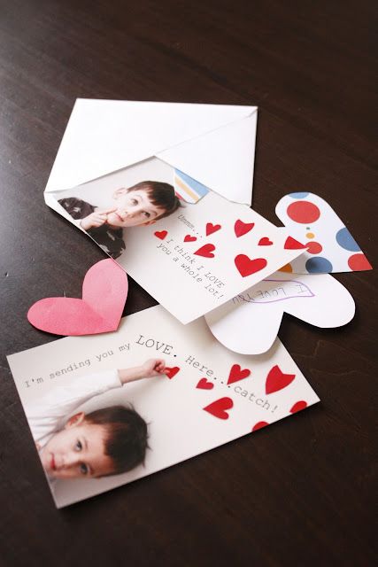 some cards with hearts on them sitting on top of a wooden table next to two envelopes