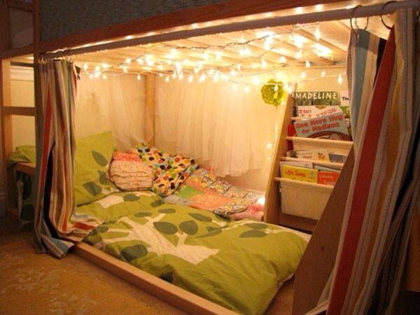 a bed with lights strung from the ceiling and curtains over it's headboard