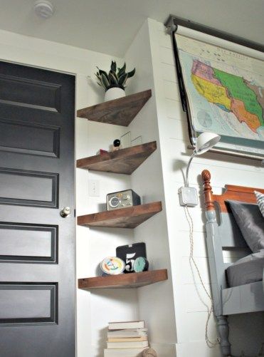 a bed room with a neatly made bed and shelves on the wall next to it